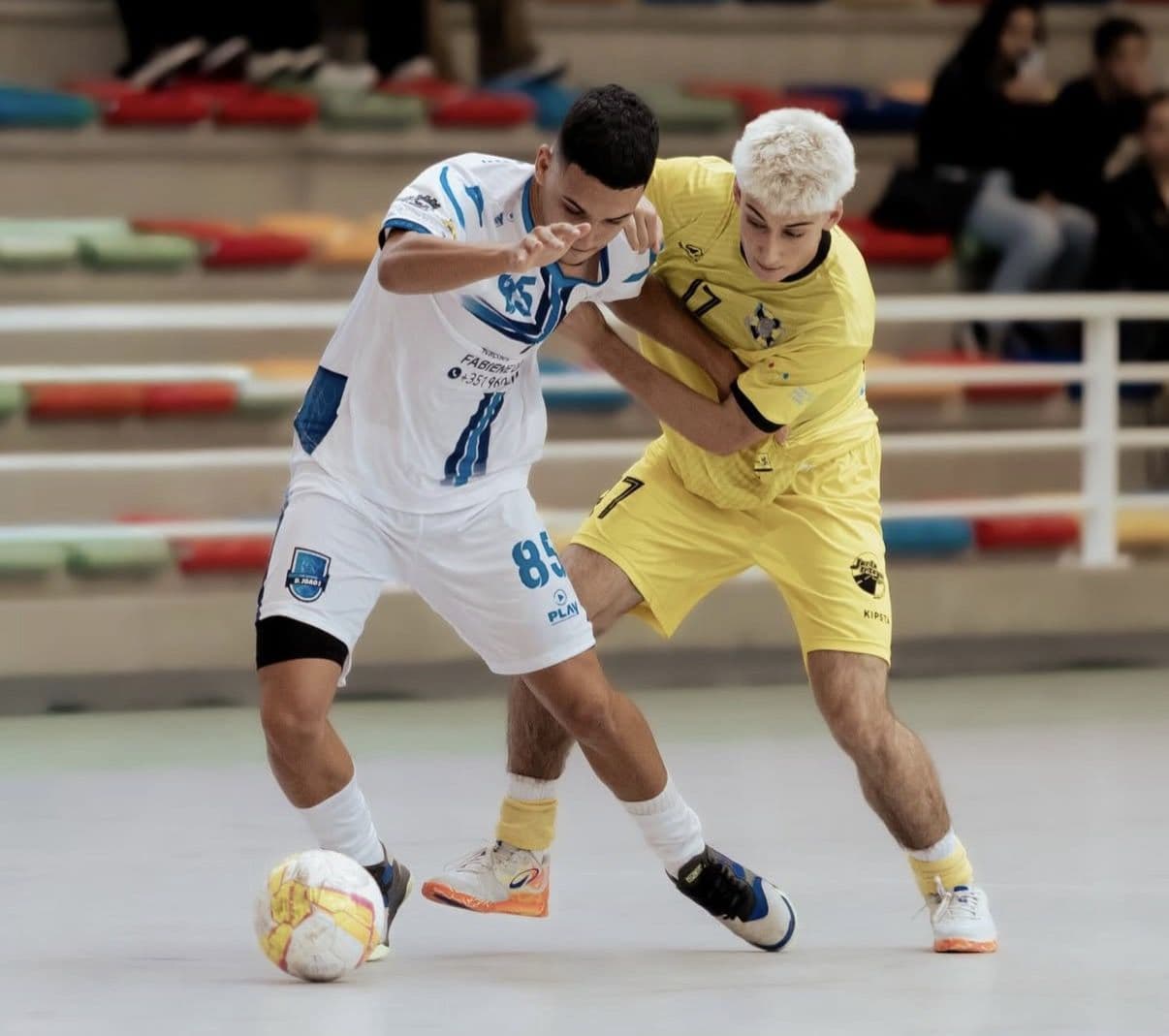Players contesting the ball in a futsal match in custom kits