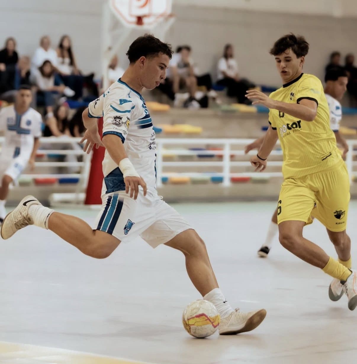 Jogador de futsal a rematar à baliza com equipamento personalizado